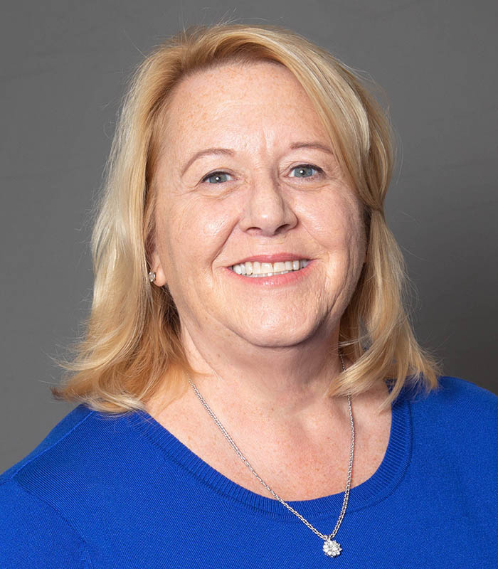 Meet Our Owner - Professional and Welcoming Group at a Conference Table Faces the Camera, Team Leader Sitting on the Table with Arms Folded